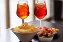 Italian aperitives/aperitif: glass of cocktail (sparkling wine with Aperol) and appetizer platter on the table.